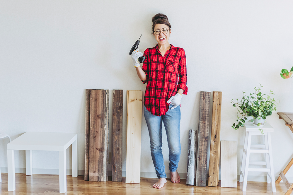 mulher com furadeira de parede para redecorar apartamento