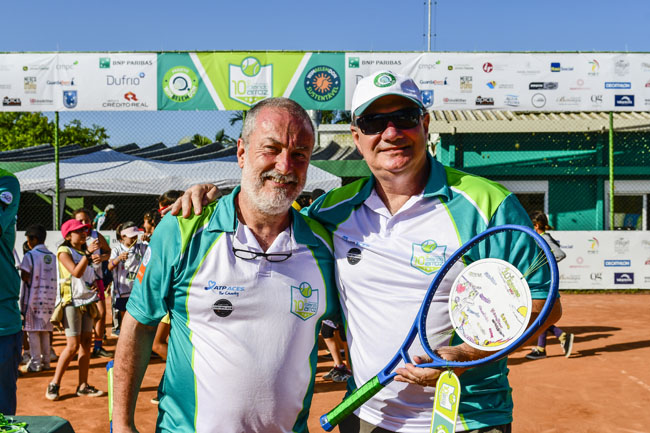 Dois homens com roupas e e raquete de tênis em um evento beneficente com patrocínio da Crédito Real.
